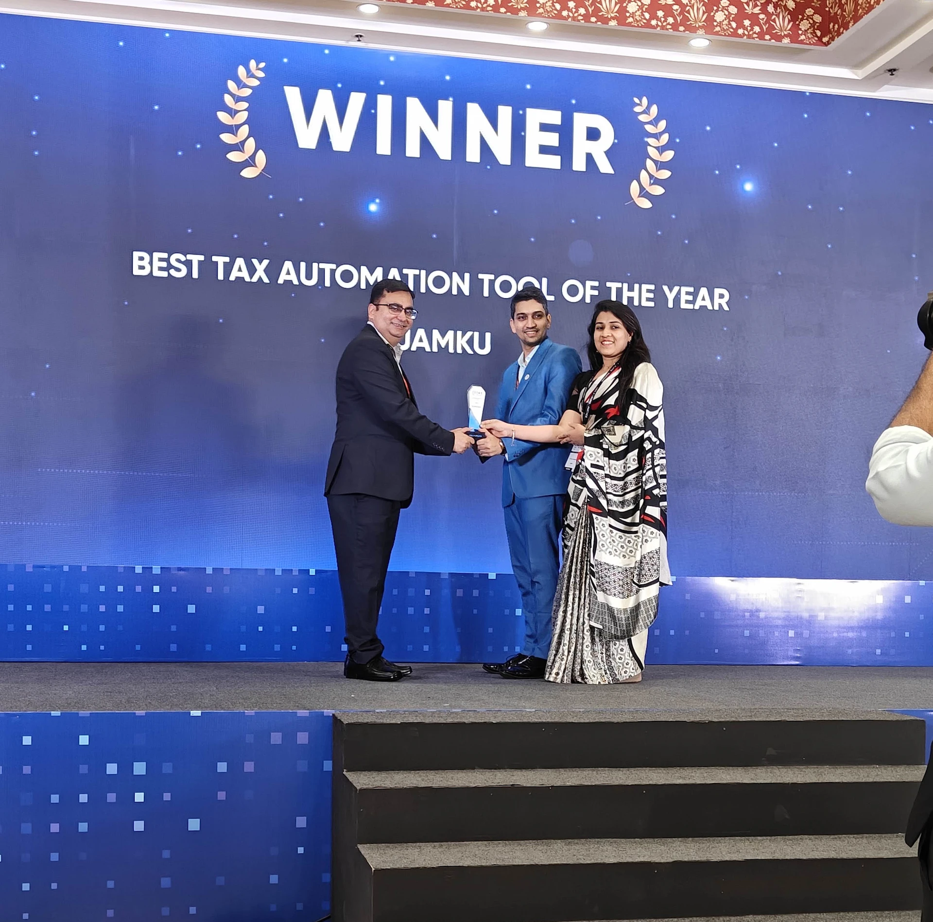 Winners holding the Best Tax Automation Tool of the Year trophy on stage beneath the WINNER backdrop in Delhi